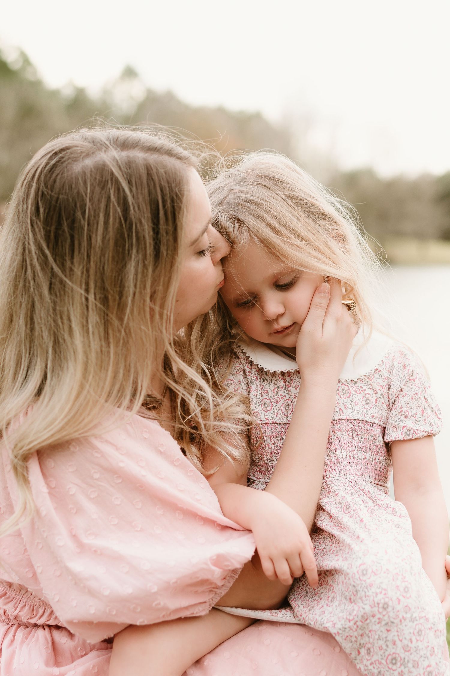 Sweet moment of affection shared while wearing pink and floral dresses outdoors.
