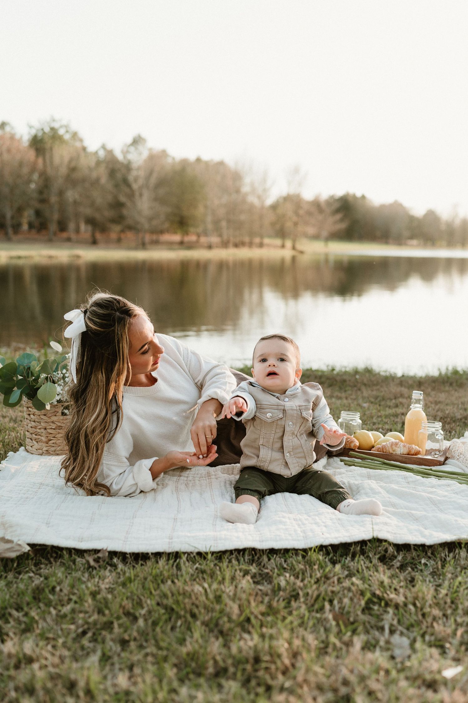 A picnic blanket laid out by a serene lake with sunflowers and citrus fruits creating a cozy outdoor setting.