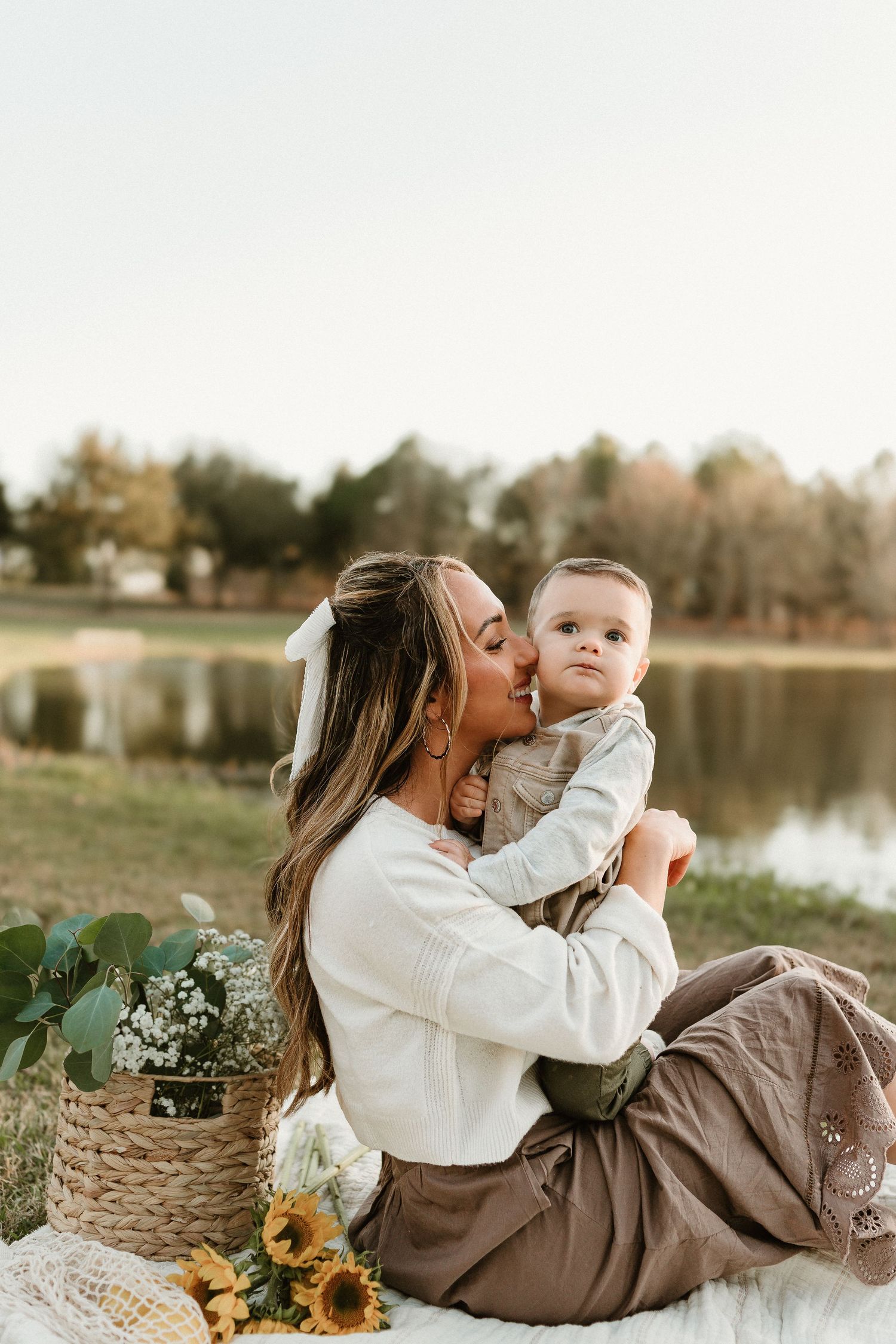 Relaxing outdoor picnic scene with sunflowers and natural decor beside a tranquil lake.