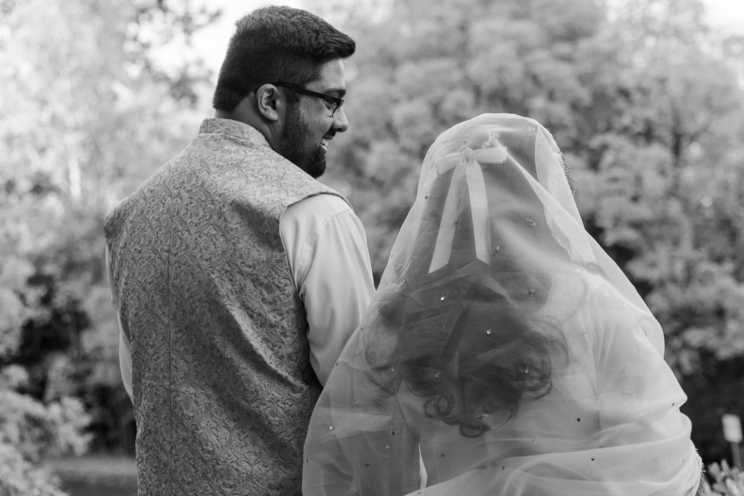 Romantic black and white portrait of a couple sharing an intimate moment under a veil.