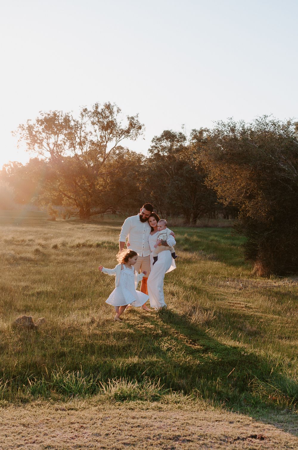 A family portrait in a field of grass, with the eldest child running rings around mum, dad and brother - Perth