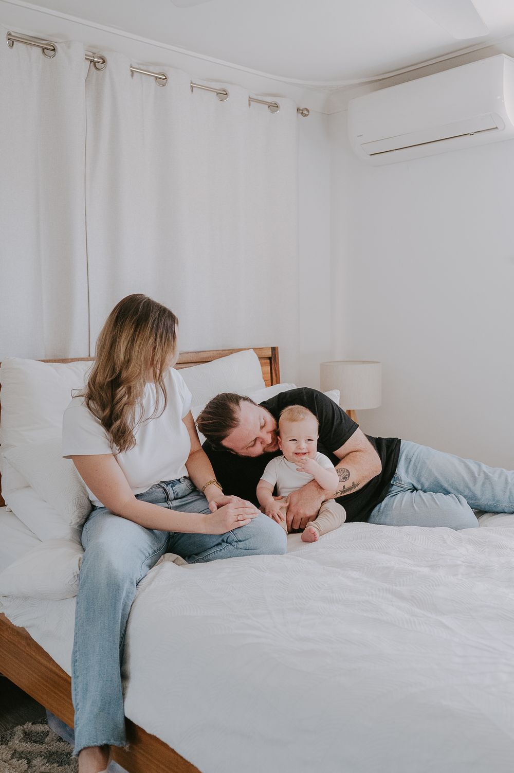 Mum, dad and baby sitting on their bed - Perth