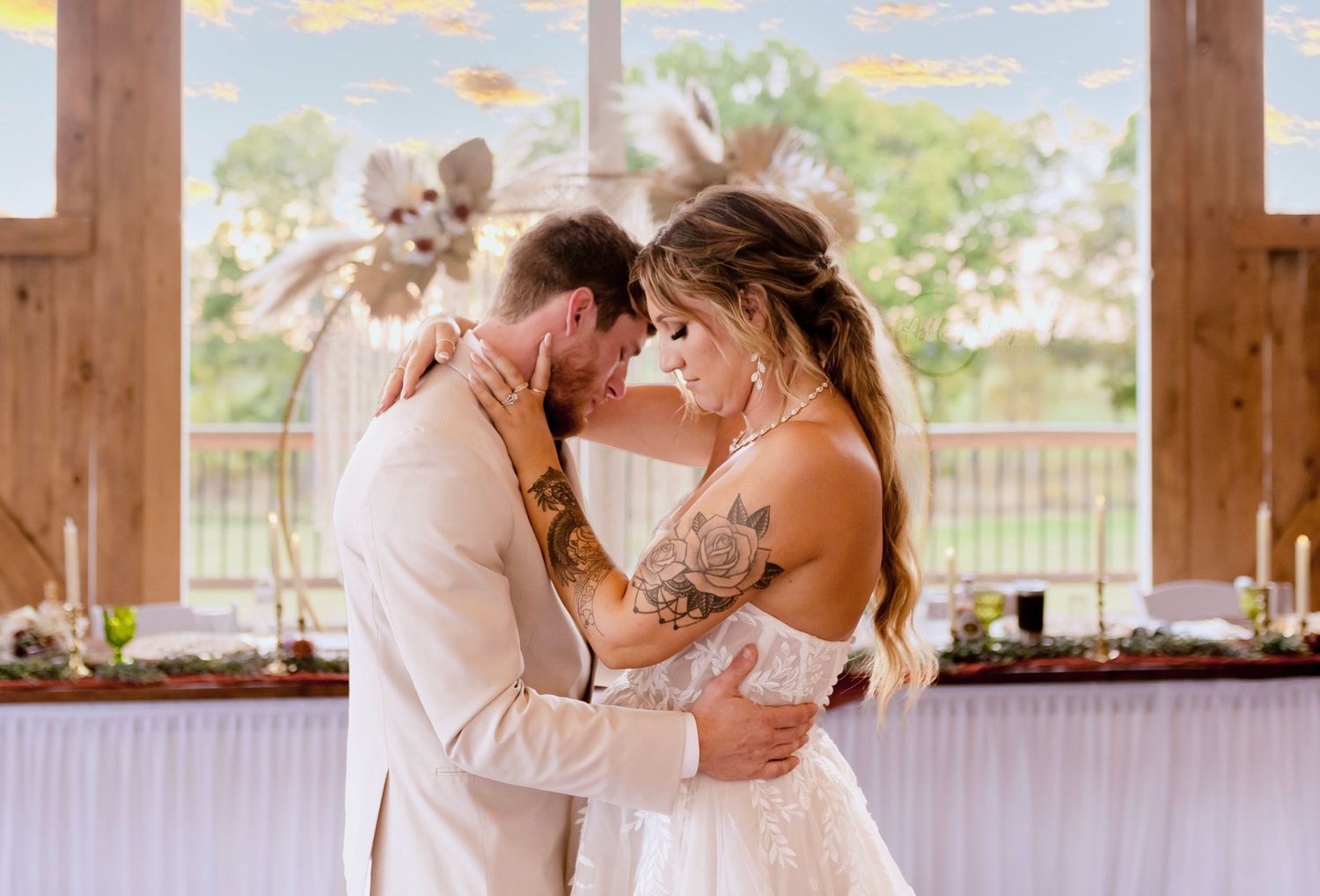 The bride and groom enjoy their first dance together, illuminated by soft lights inside a charming barn.