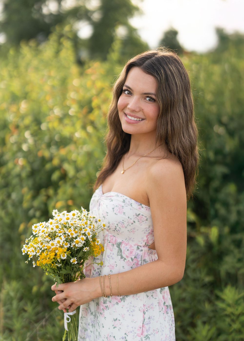 A white floral sundress against a summery field backdrop with wildflowers in bloom and natural lighting.