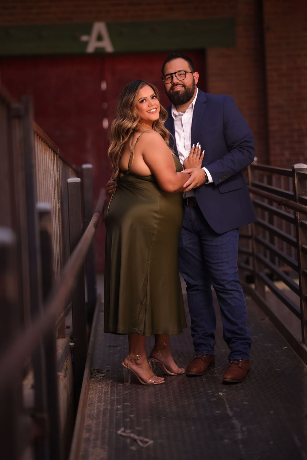 Couple poses together on wooden walkway during evening photoshoot.