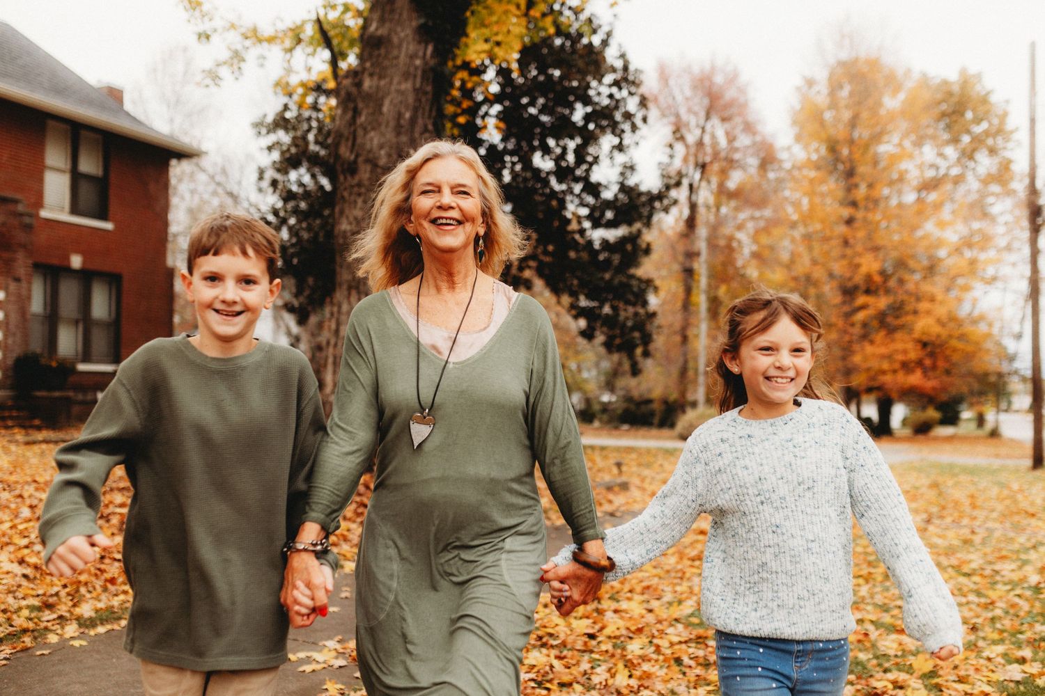 Grandmother holding the grandchildren's hands crossing a street