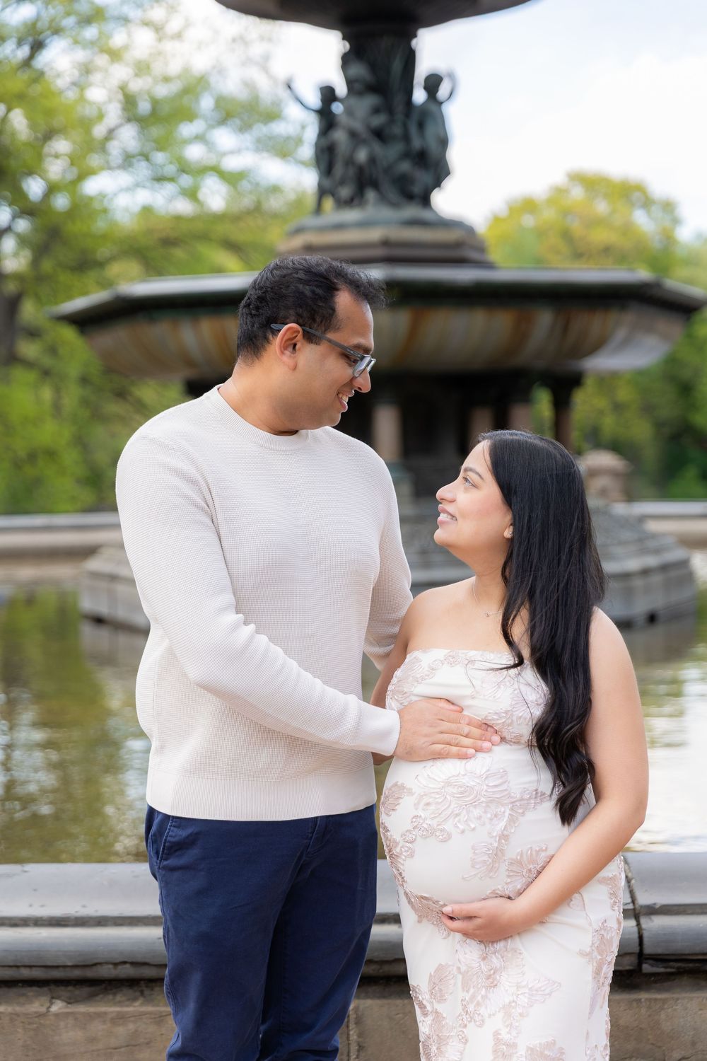 Pregnant couple poses lovingly in front of Bethesda Fountain in Central Park, NYC.