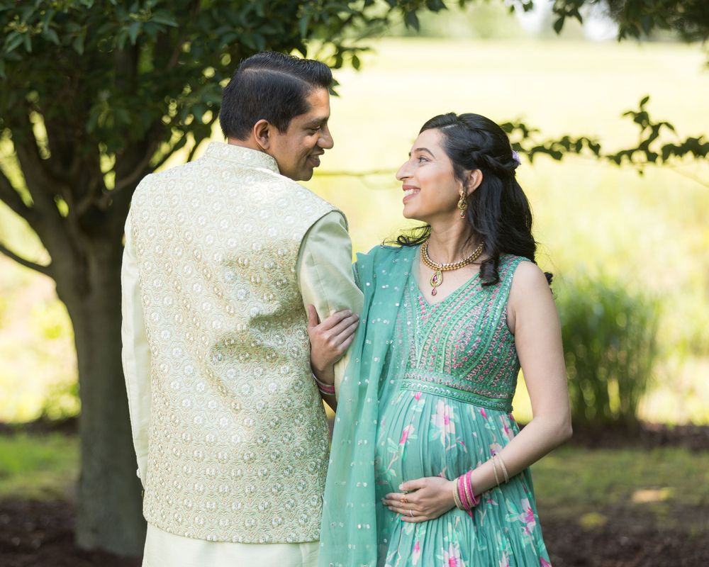 A tender moment captured between a couple in traditional Indian attire against a garden backdrop.