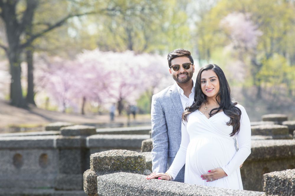 Spring wedding portrait by stone wall with cherry blossoms in background.