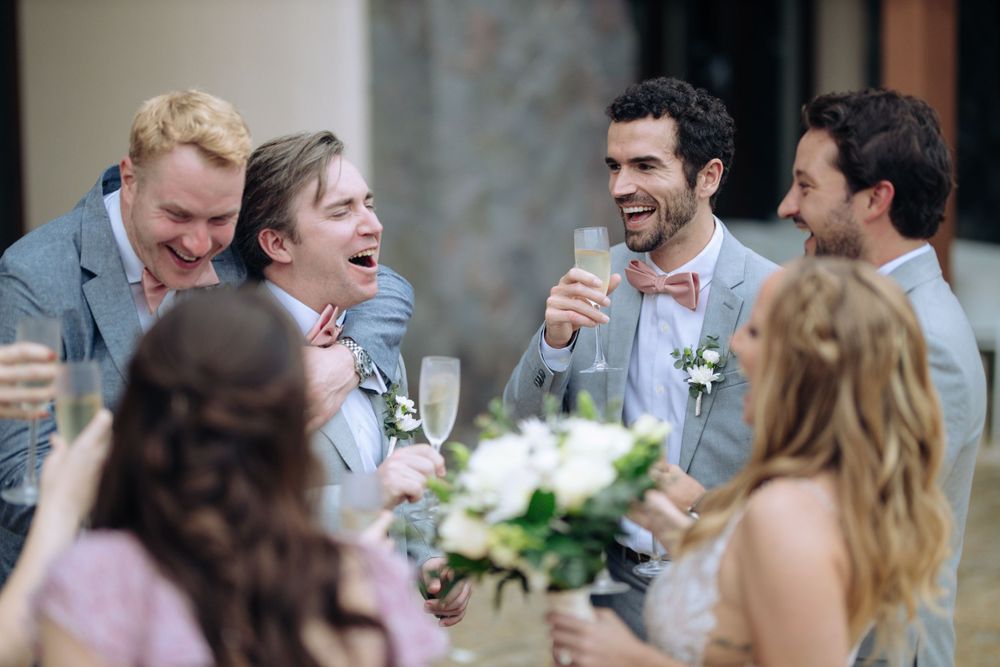 Wedding guests share laughter during an outdoor reception celebration.