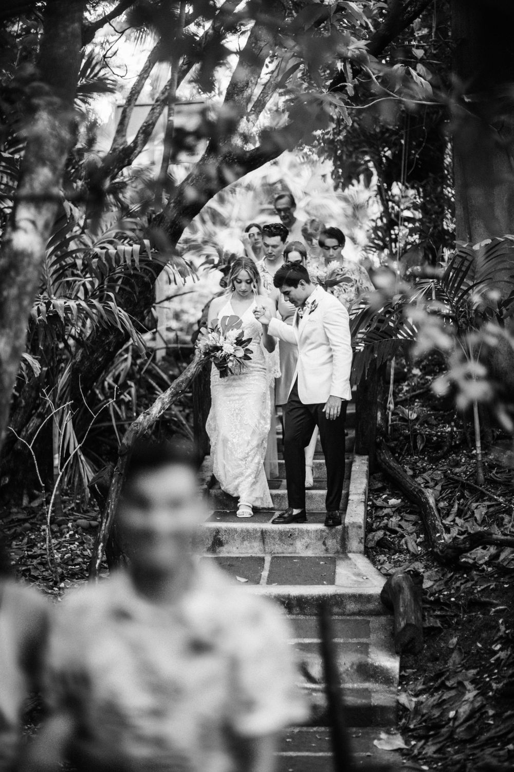 Black and white wedding photograph in a lush garden setting.