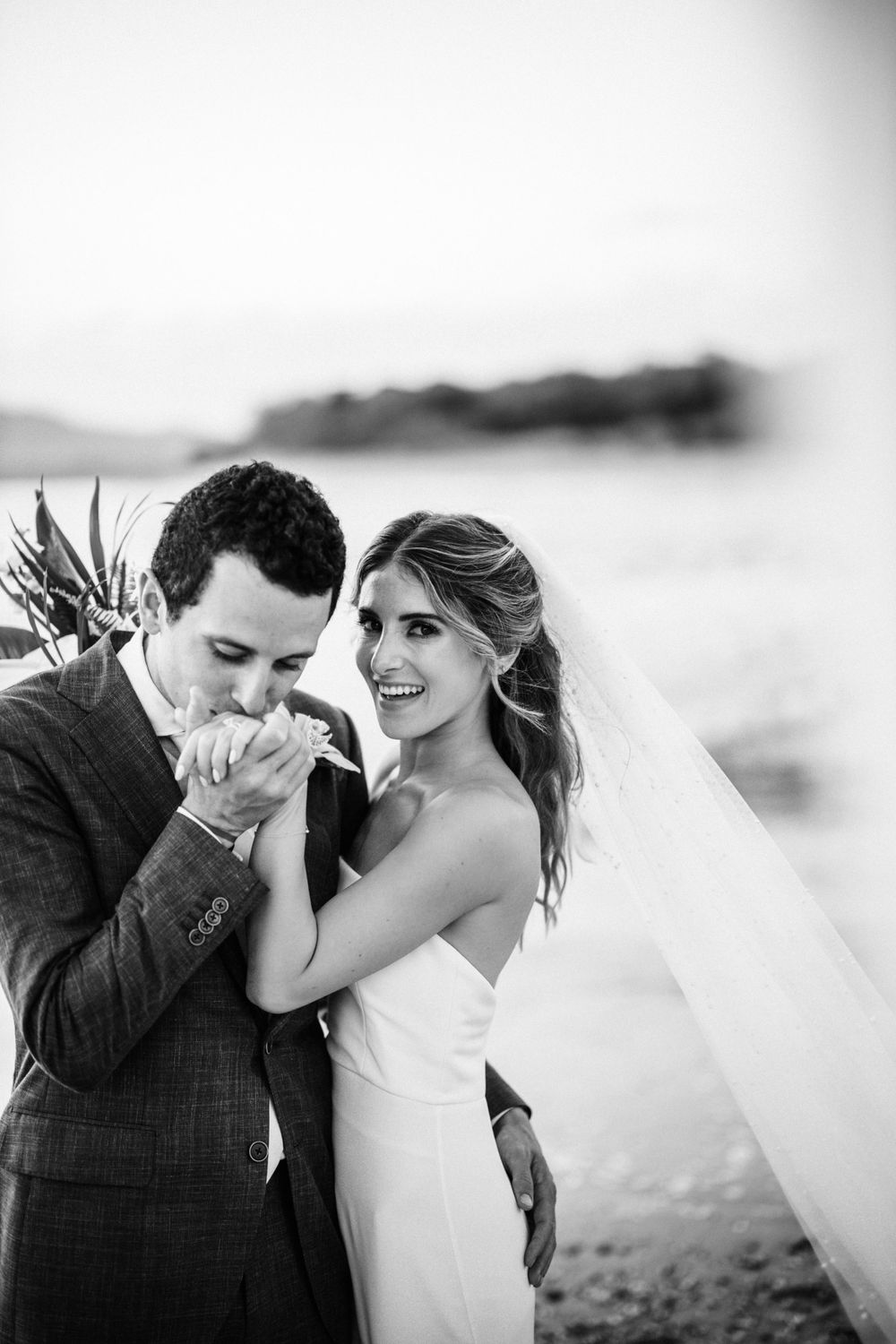 Black and white beach wedding photo capturing an intimate romantic moment.