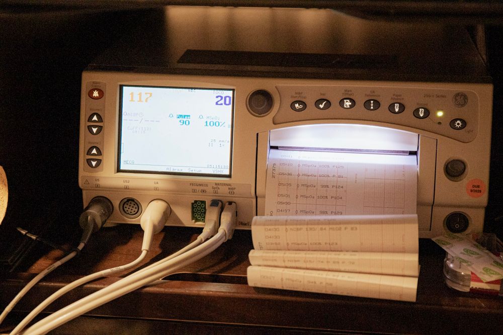 Medical monitoring equipment display and control panel in hospital room.