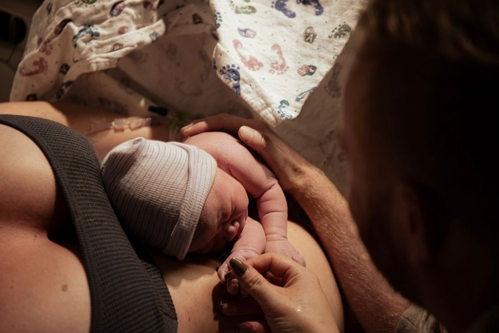 Newborn baby being cradled and examined in hospital after birth.