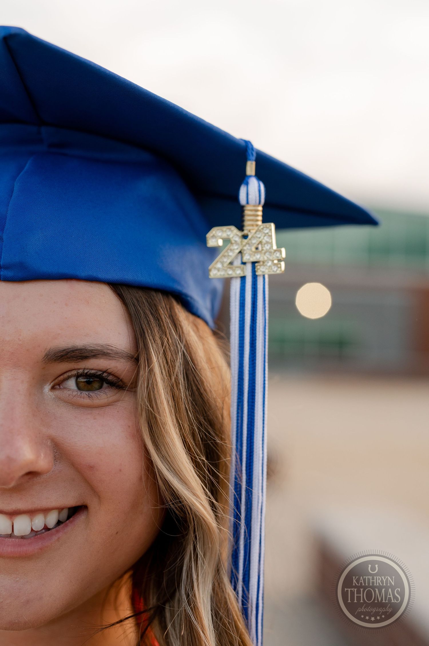 Close-up of blue graduation cap with 2024 tassel against blurred background.