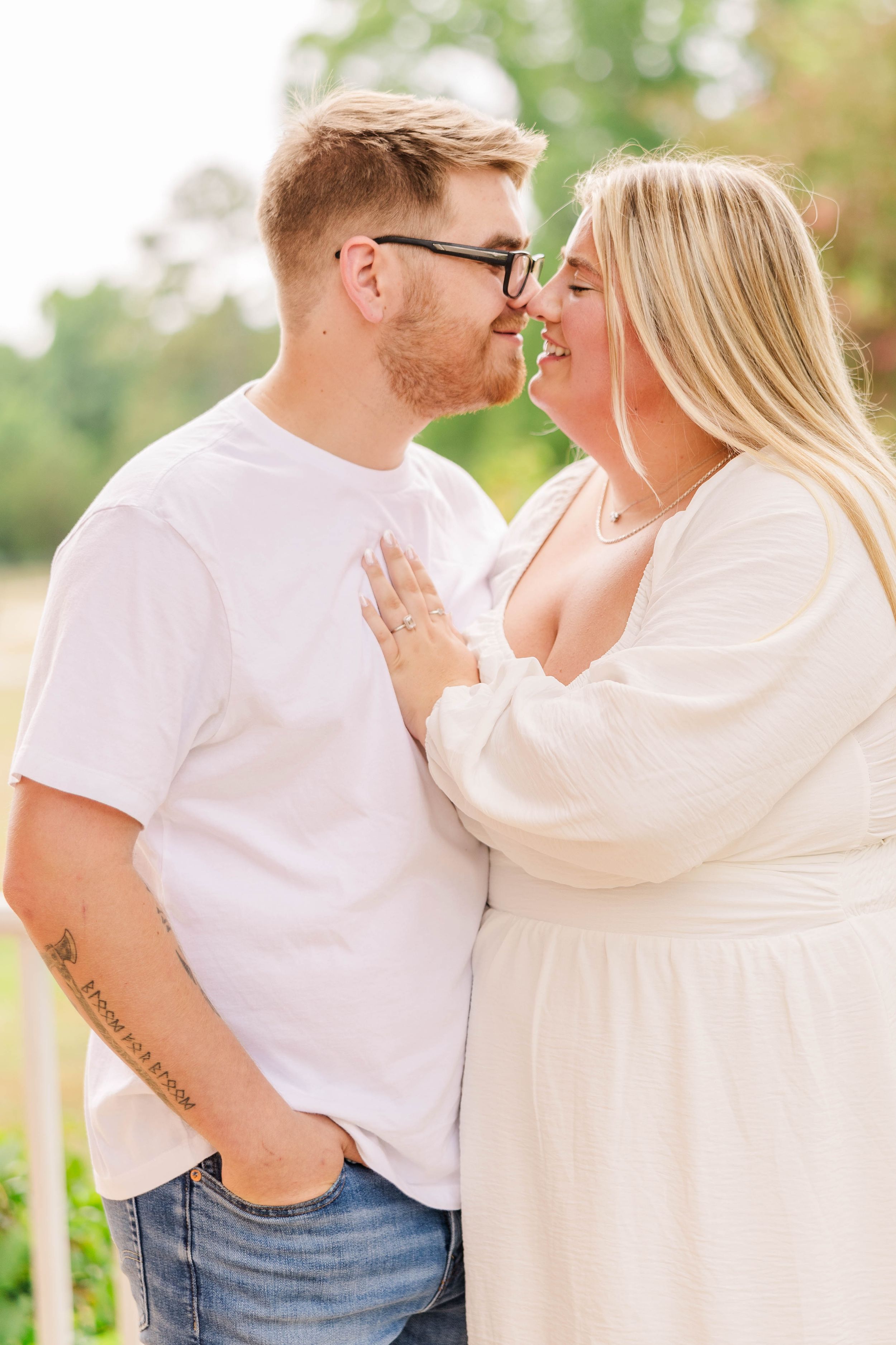 Couple in casual white outfits share tender moments on an outdoor porch.