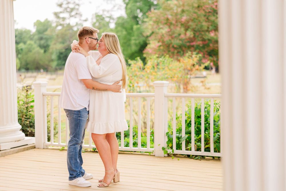 Romantic outdoor photoshoot with white columns and greenery in background.