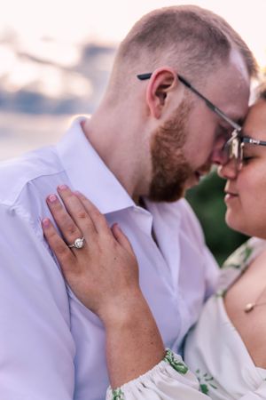 Close up of a romantic outdoor moment with an engagement ring prominently displayed.