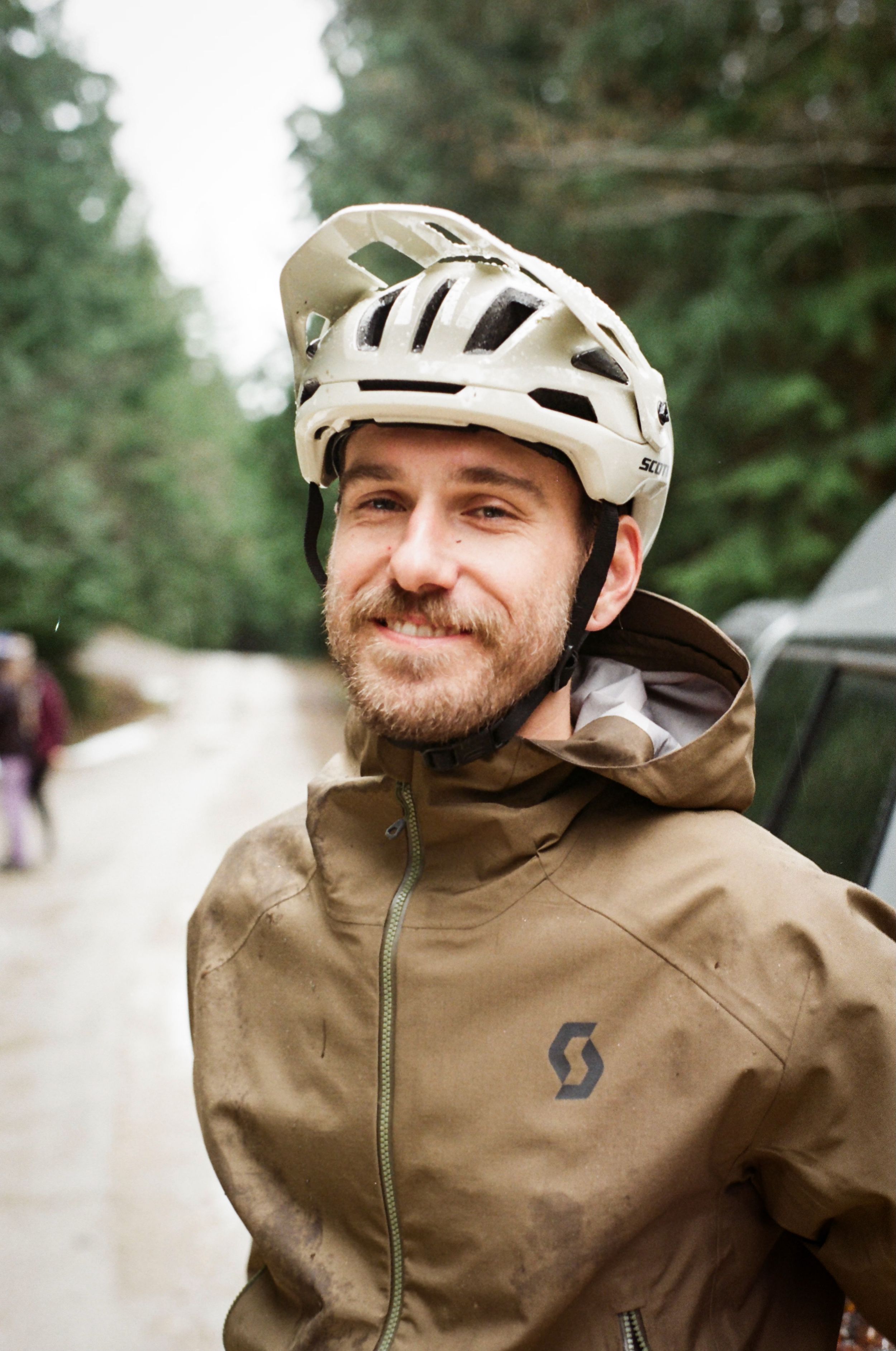 Mountain biker Joel Ducrot in tan jacket and white helmet ready for trail riding.