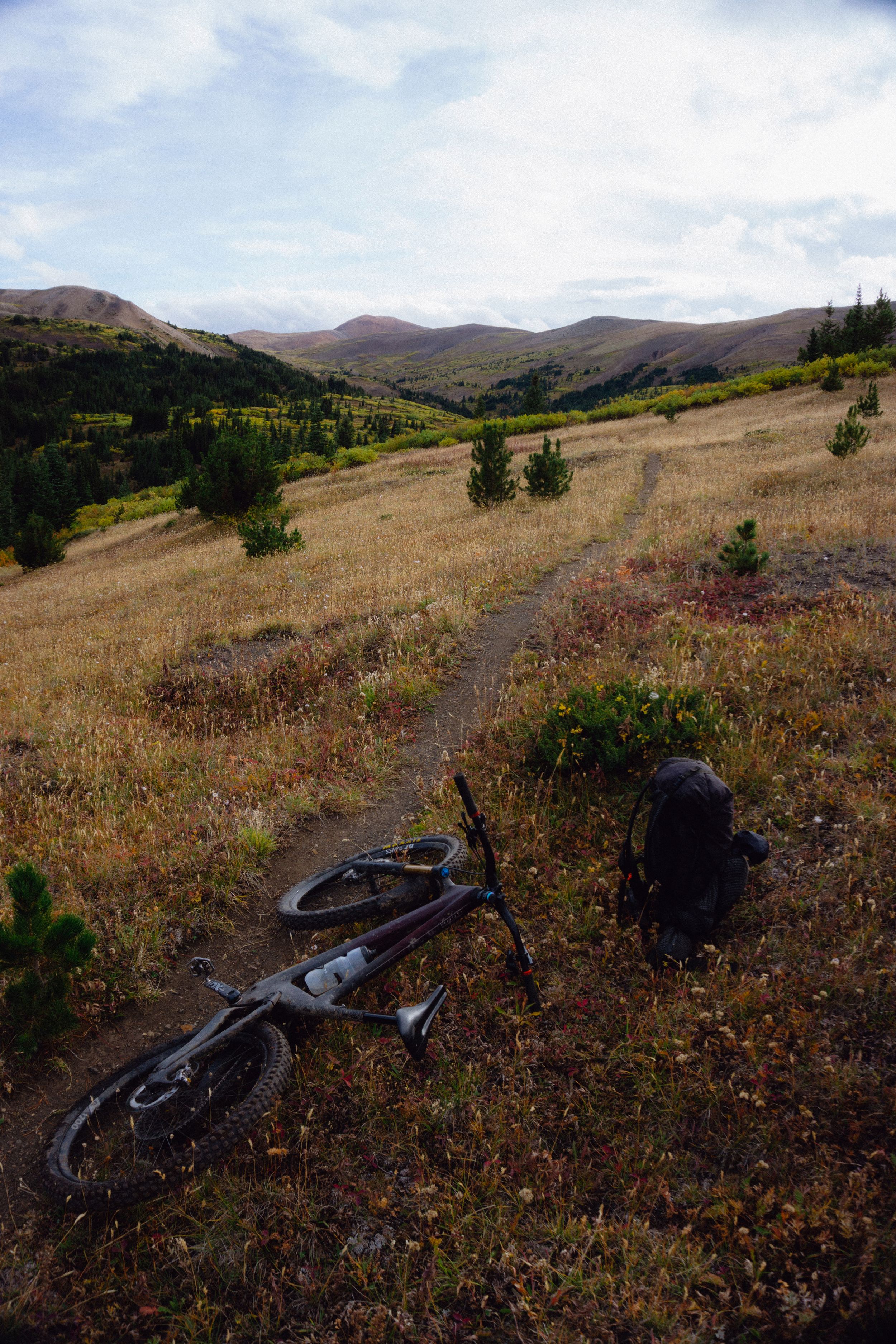 Mountain bike rests on hillside trail overlooking rolling mountain landscape in the South Chilcotins.