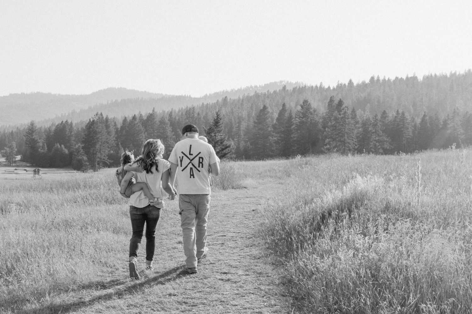 family-walking-through-a-field-holding-hands-with-mountains-in-the-background