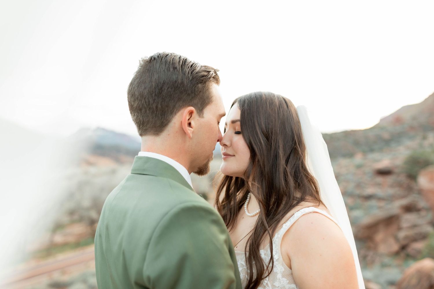 Romantic wedding photo in desert landscape with mountain backdrop in Zion National Park.