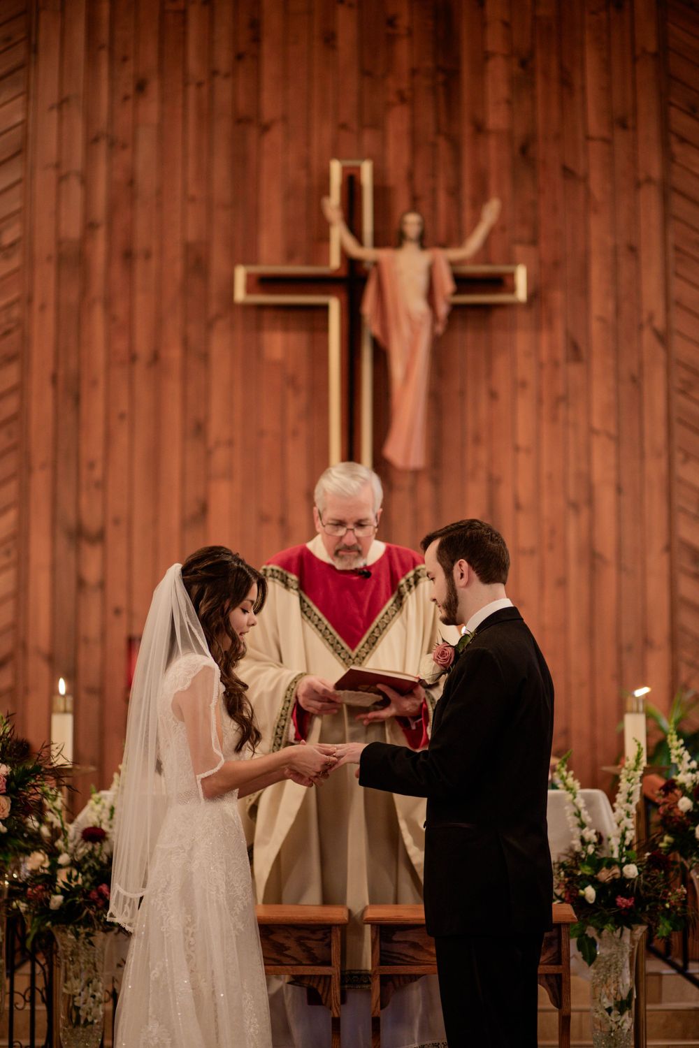 Traditional church wedding ceremony with wooden cross backdrop and floral decorations.