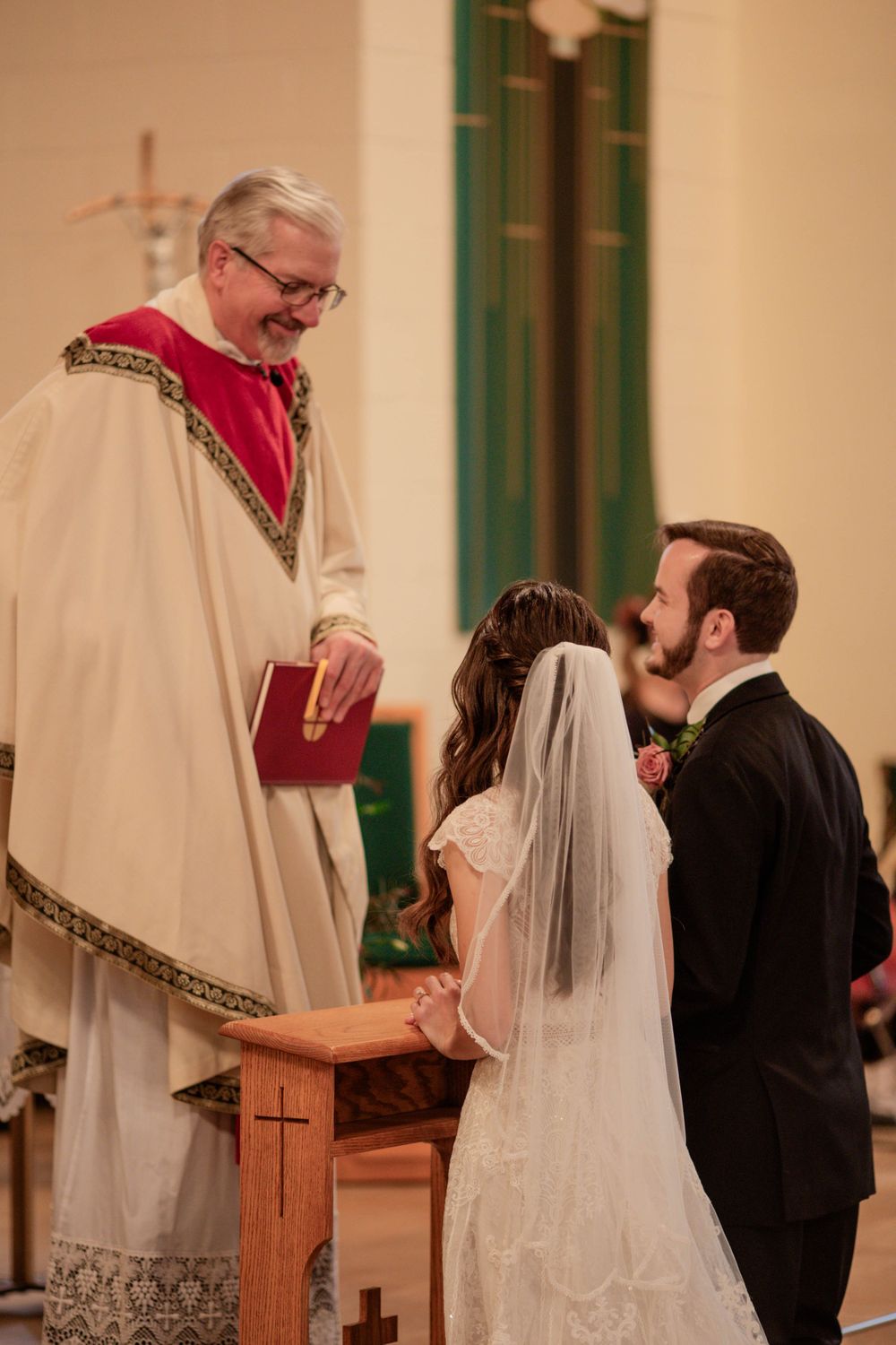 Intimate church wedding ceremony with traditional Catholic elements and wooden altar.