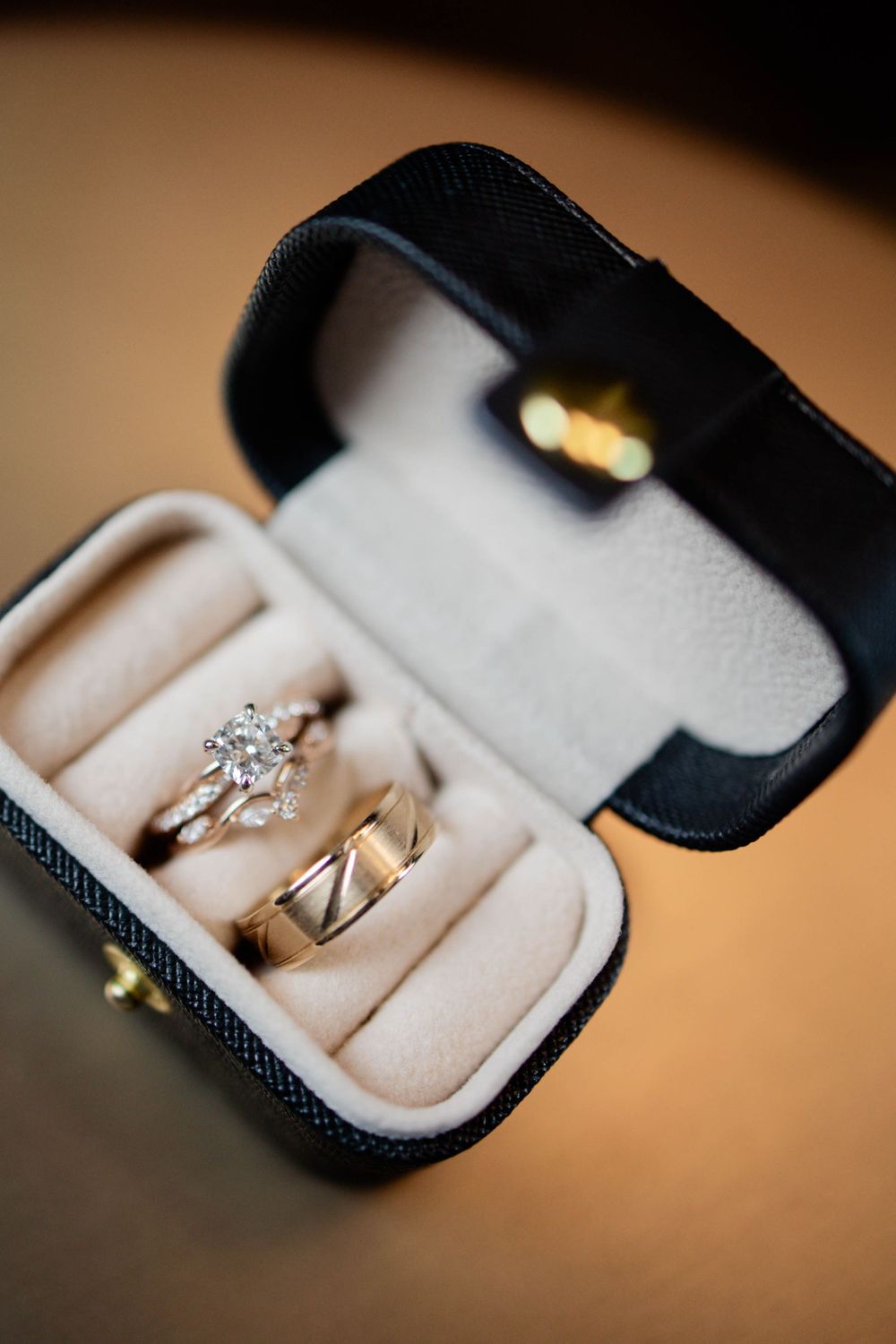 Wedding rings nestled in black leather jewelry box with cream velvet lining.