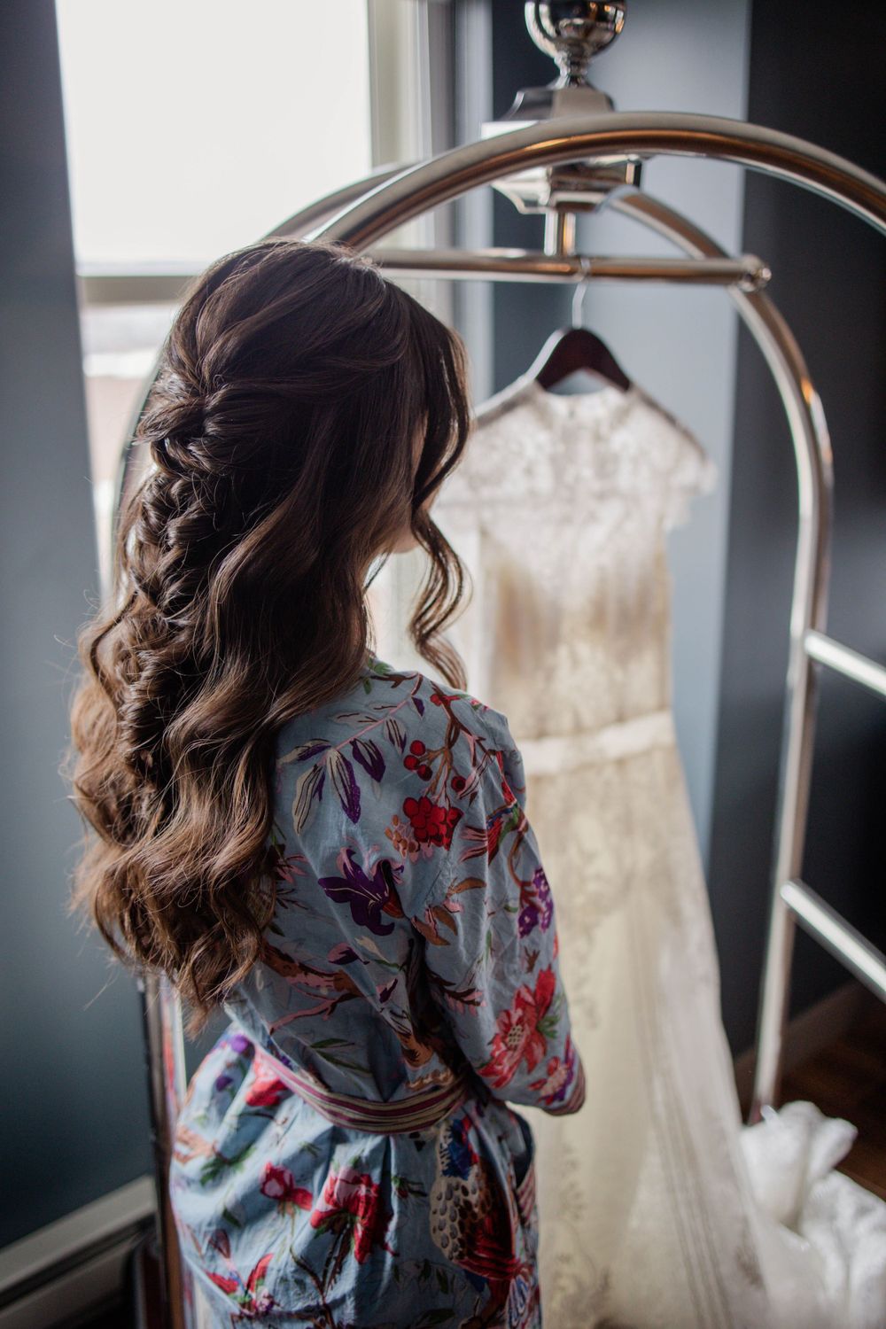 Back view of styled hair and floral robe looking at wedding dress on display.
