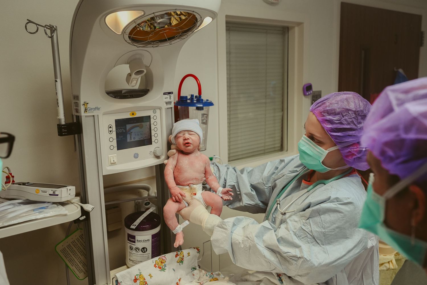 Nurse holds newborn baby girl up in operating room after a cesarean section at St. Thomas Ascension in Nashville, Tennessee.