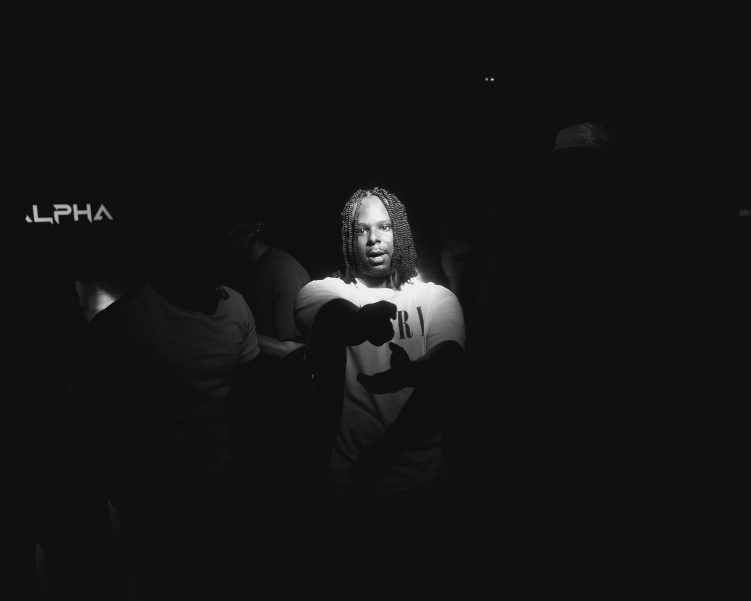 Dramatic black and white performance photograph in low-key lighting.