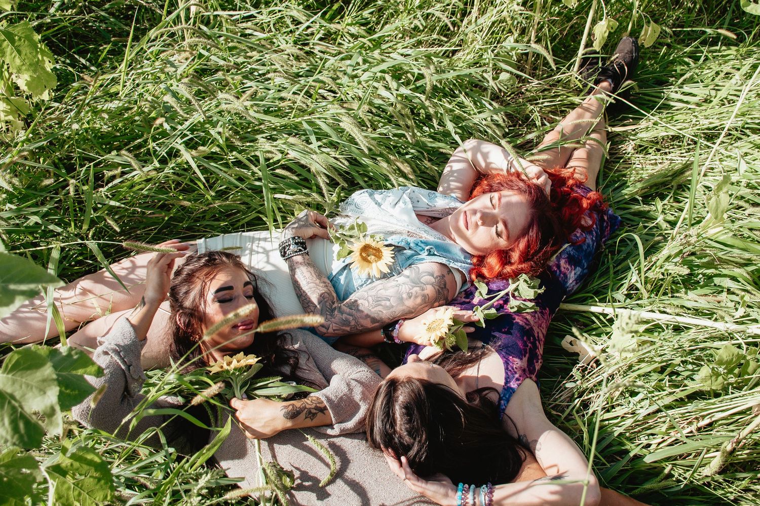 Friends lying in tall grass having a picnic on a sunny day.
