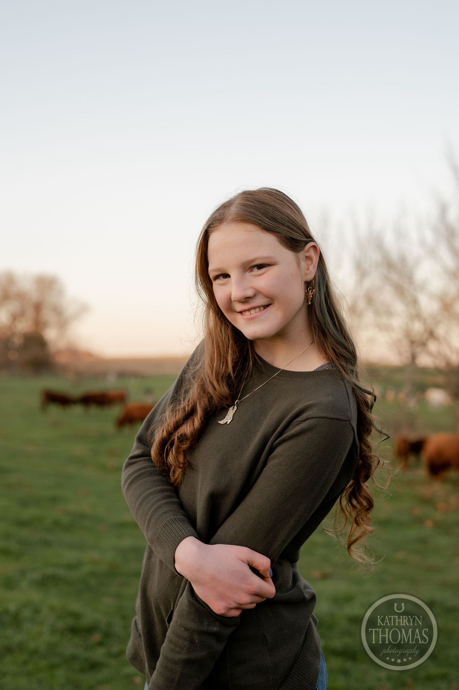 A warm sunset portrait in a countryside setting with cattle in the background.