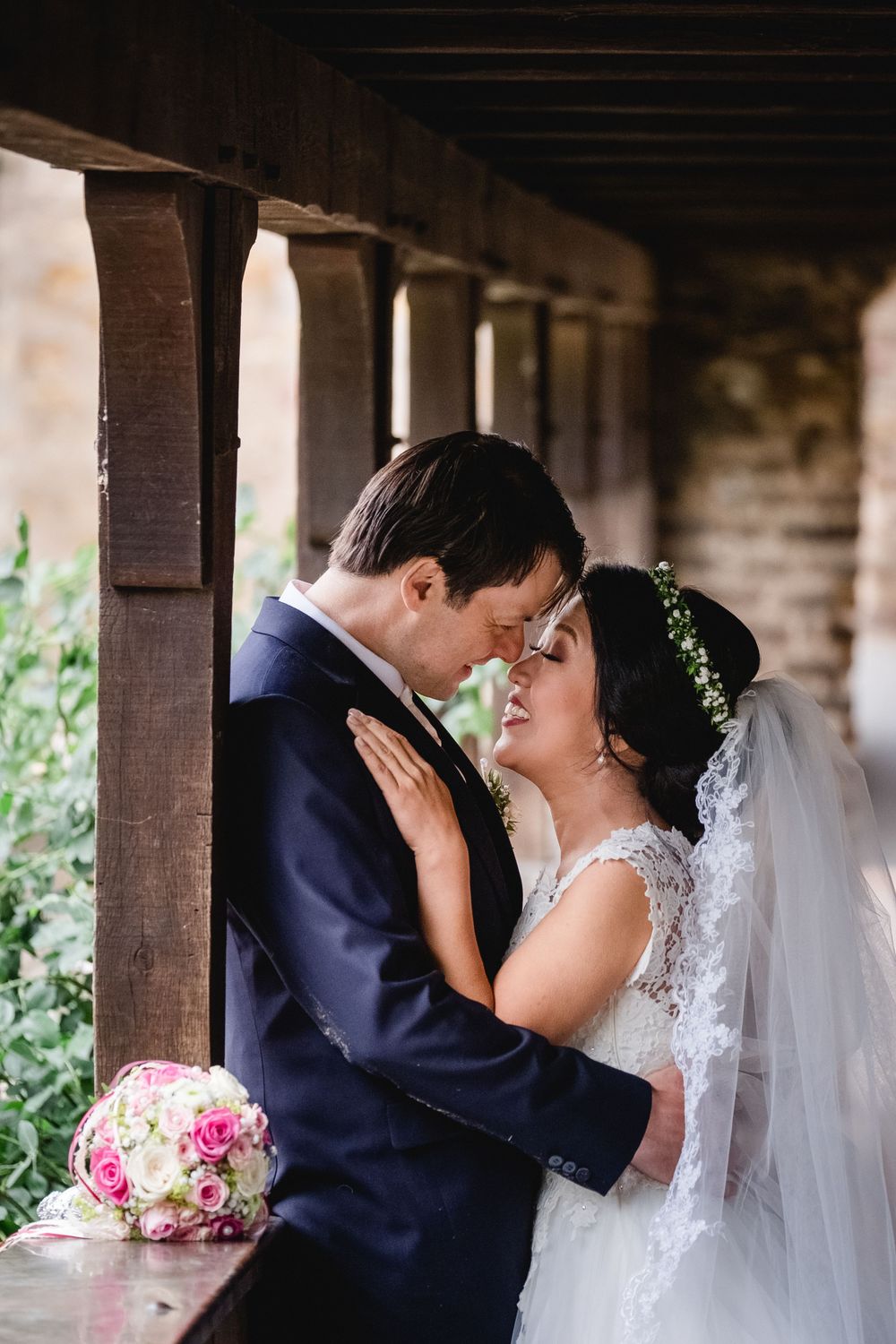 Intimate moment between newlyweds in covered walkway with floral decor.