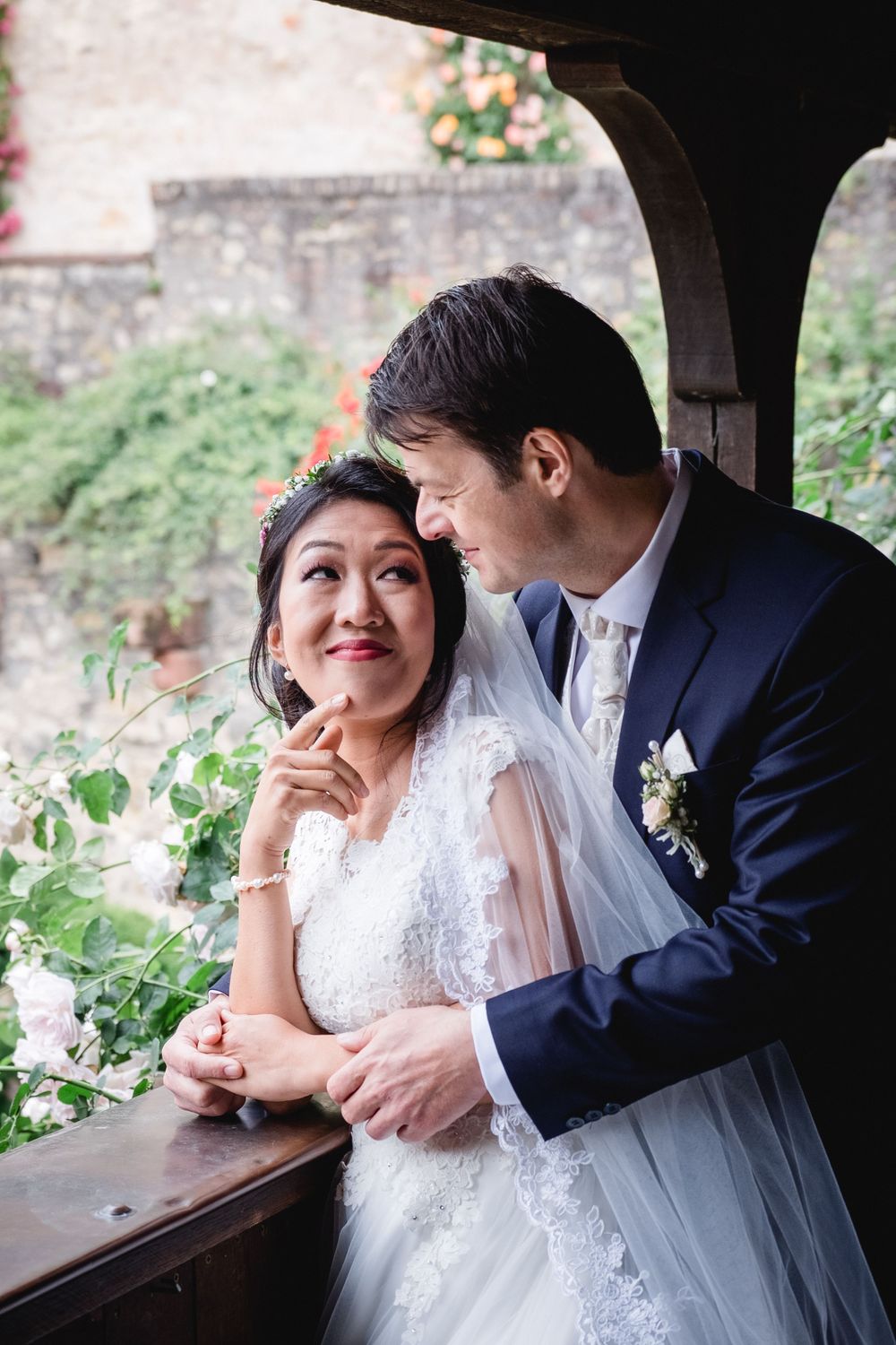 A couple shares a tender moment in an arched window overlooking a garden.
