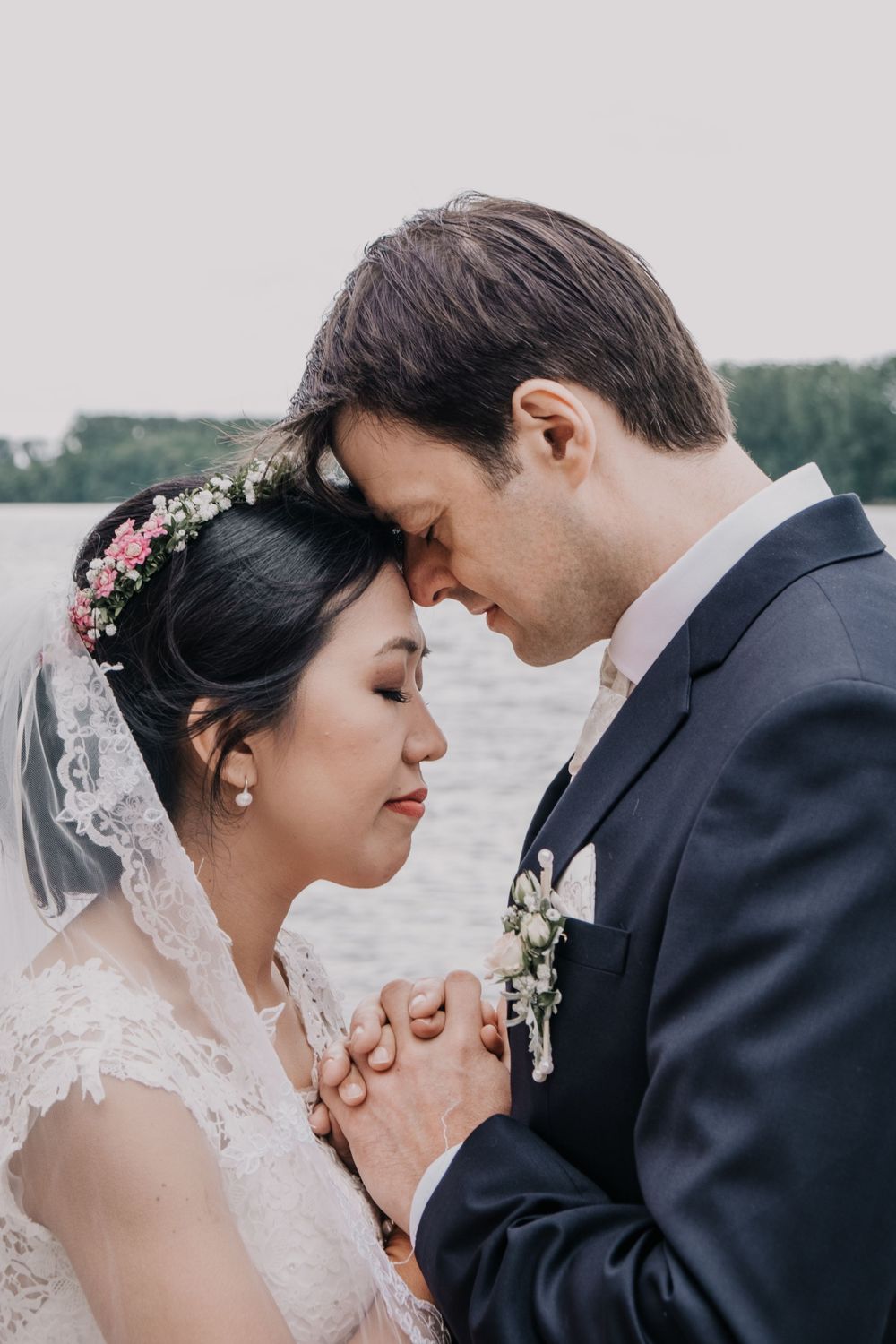 A tender moment between newlyweds with foreheads touching and hands clasped.