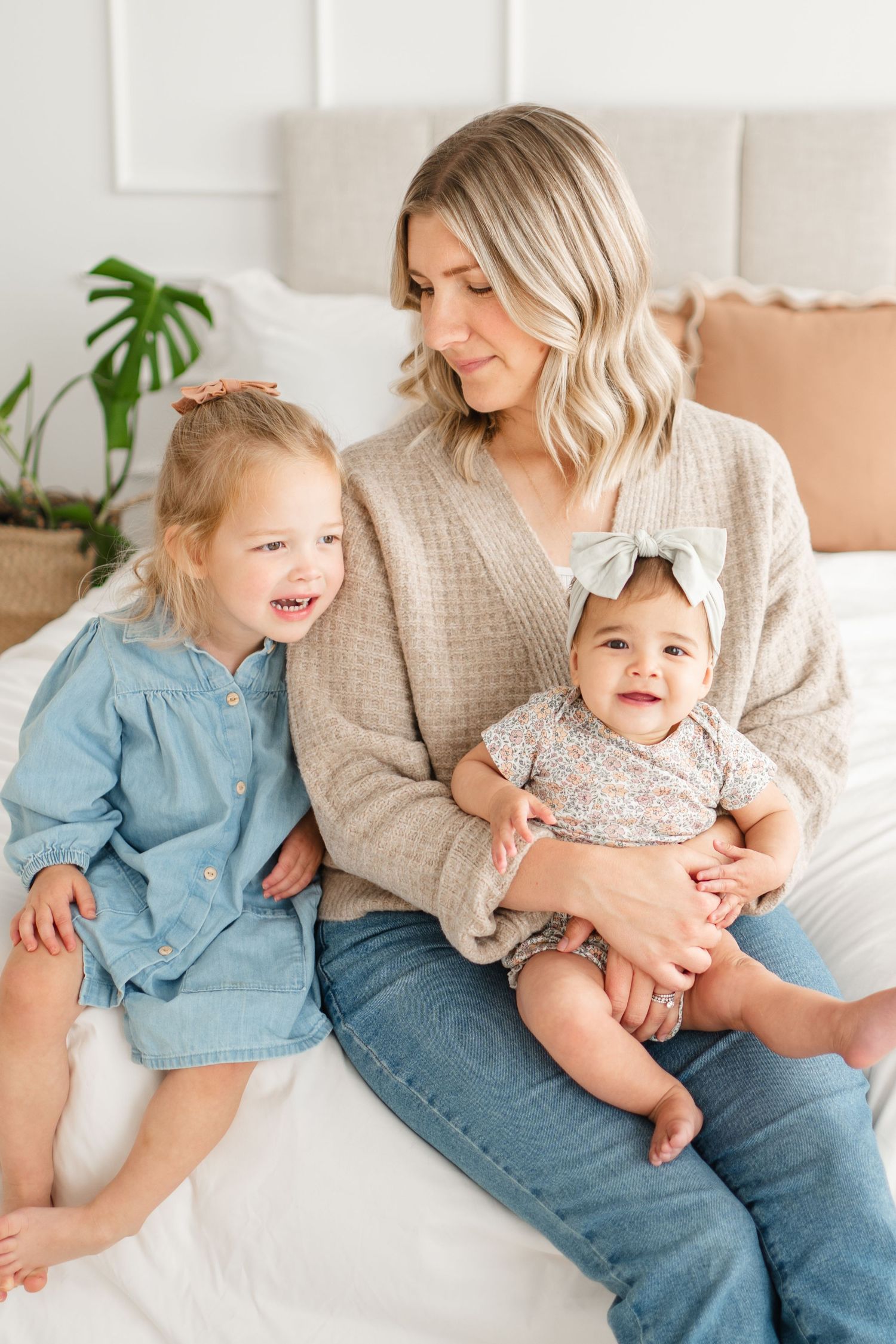 A cozy family moment on a white couch with a houseplant in the background.