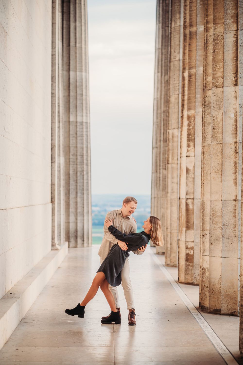 A dancing couple between classical stone columns with dramatic lighting.