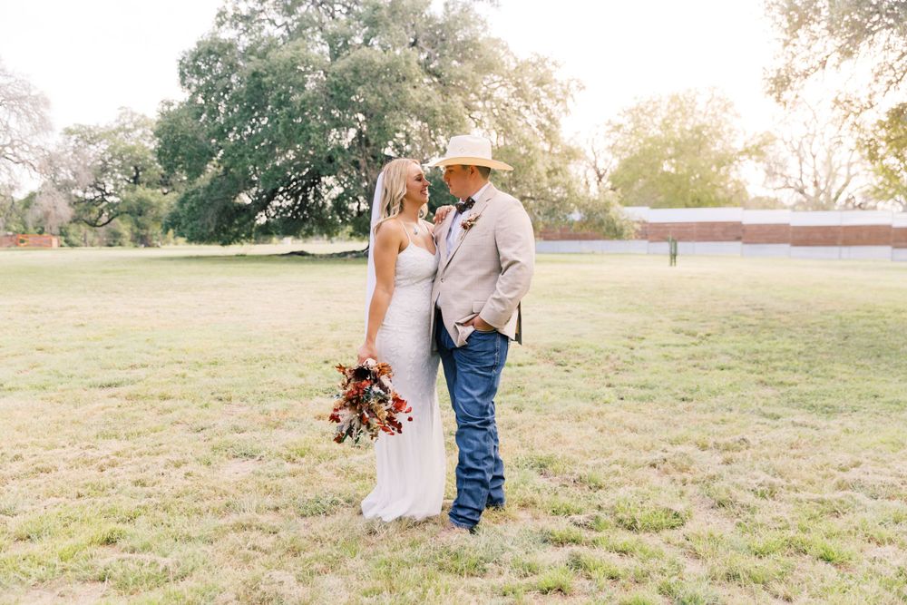 Candid moments of newlyweds walking together in a sunlit field during golden hour.