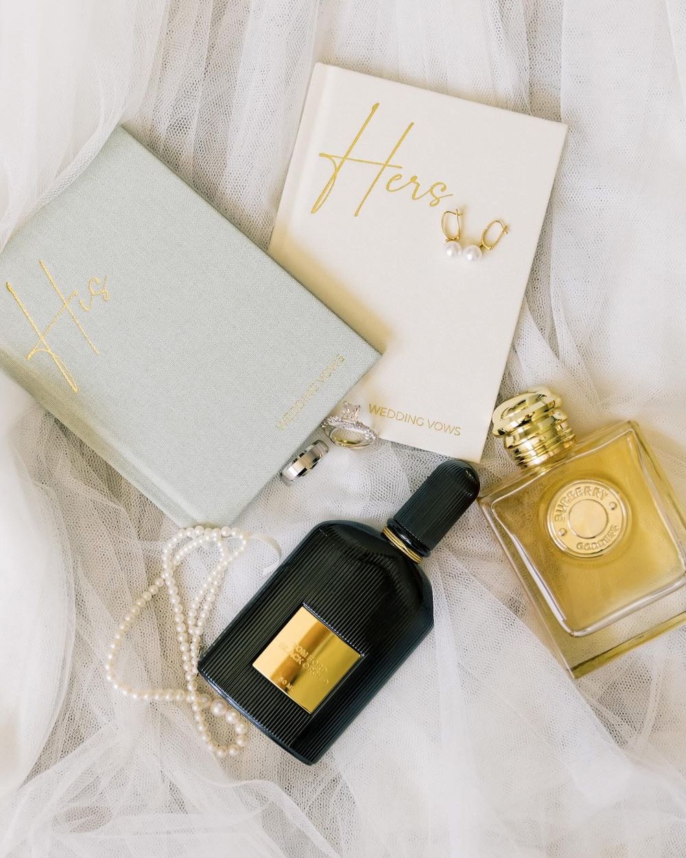 Wedding perfume bottles and white accessories styled on delicate tulle fabric.