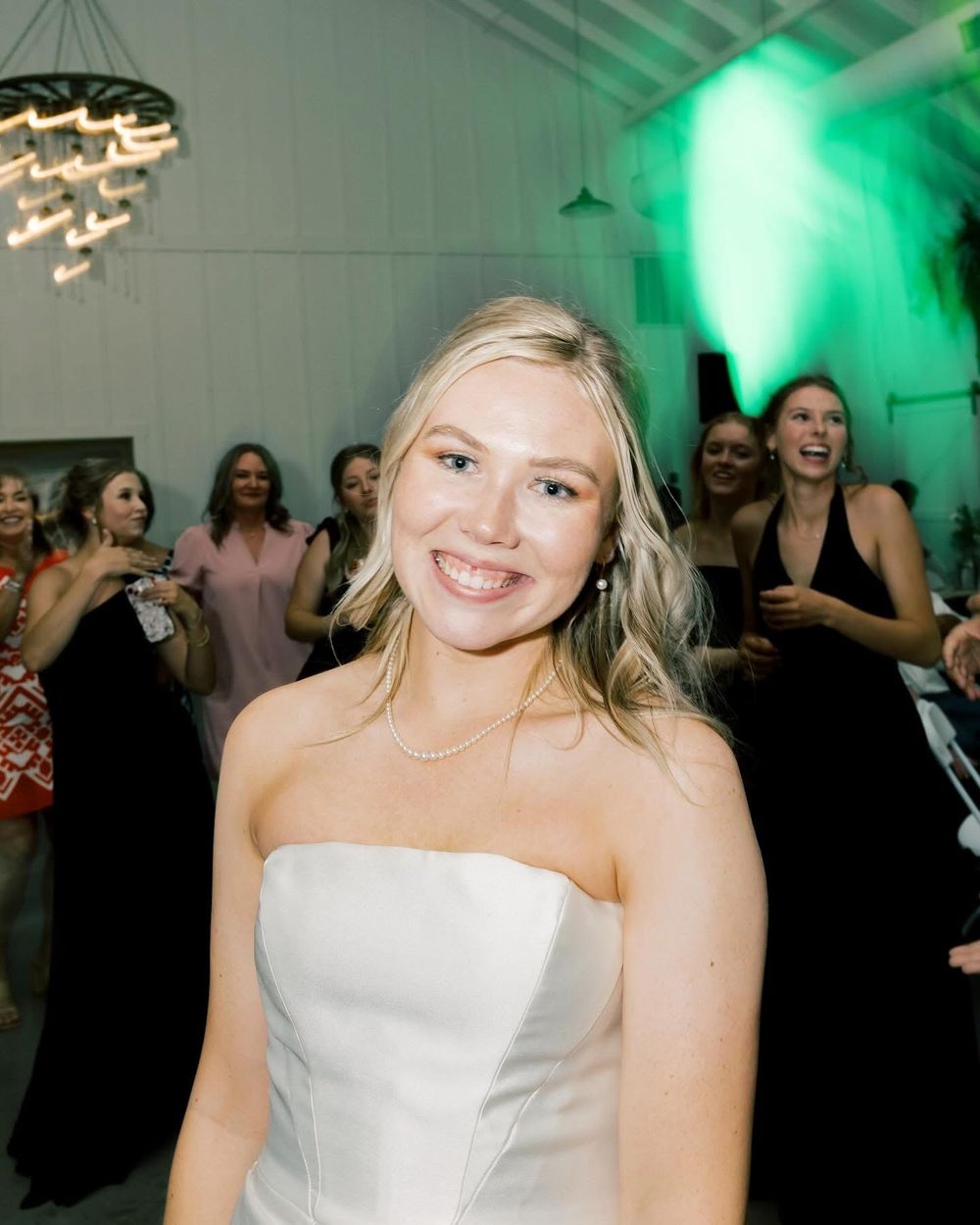 Bride celebrating at a reception with ambient green lighting.