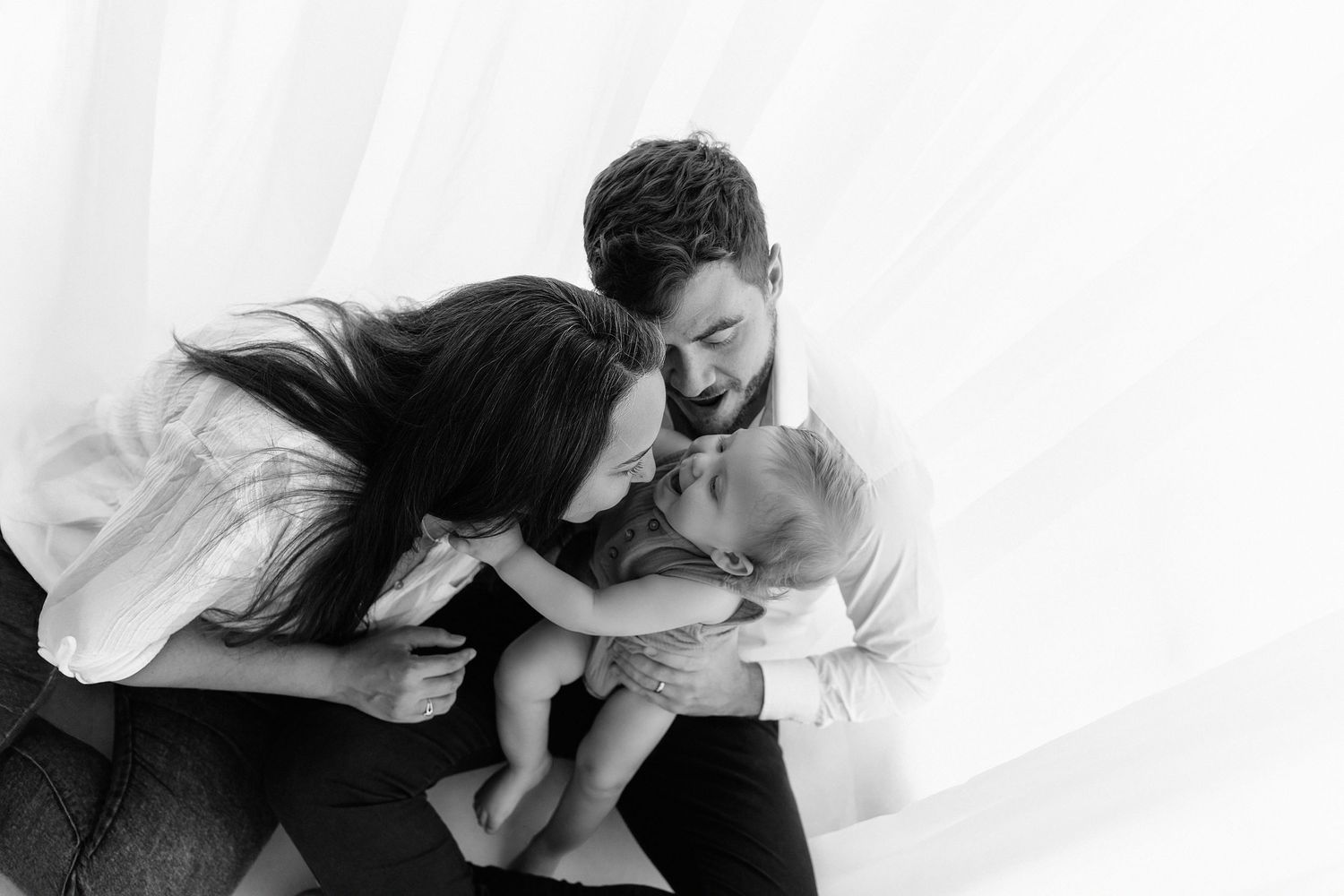Intimate black and white family portrait against white background.