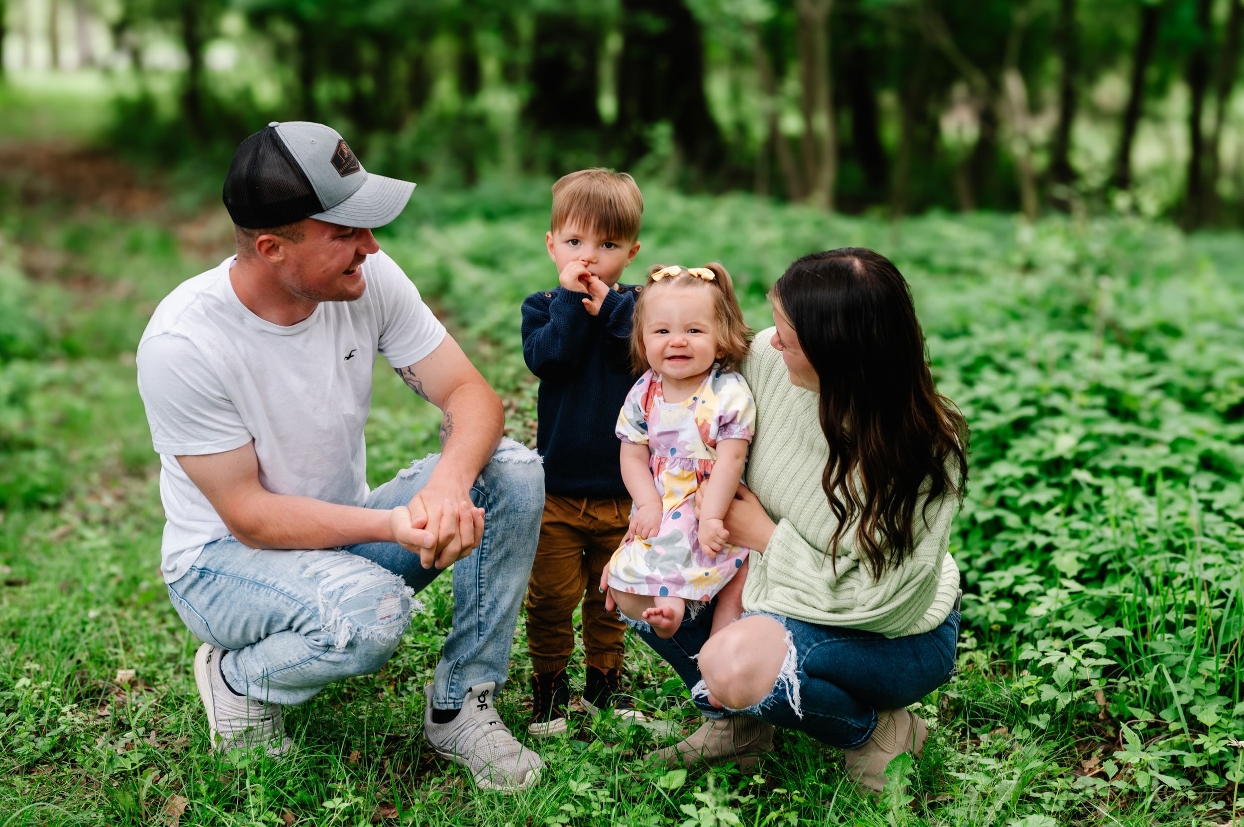 A family spends time together outdoors surrounded by lush green foliage in a forest setting.