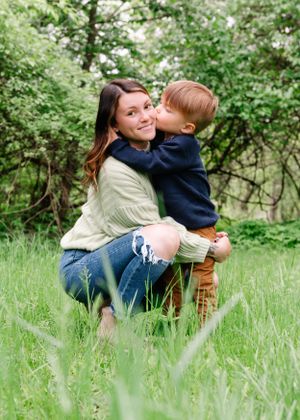 A sweet moment between parent and child embracing in a field of tall grass and trees.