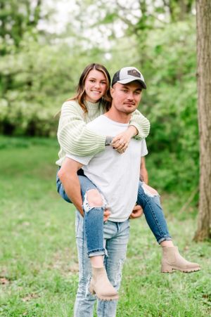 A playful piggyback ride moment captured outdoors in a green spring setting.