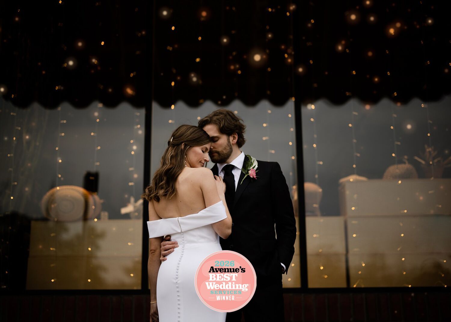 Bride and groom embracing under string lights at a Calgary wedding reception, Tkshotz