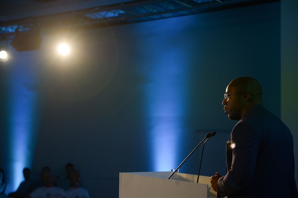 Professional conference stage setup with blue lighting and presentation screen in dark auditorium.