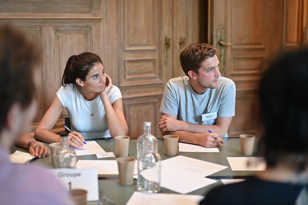 Business meeting participants taking notes at wooden conference table.
