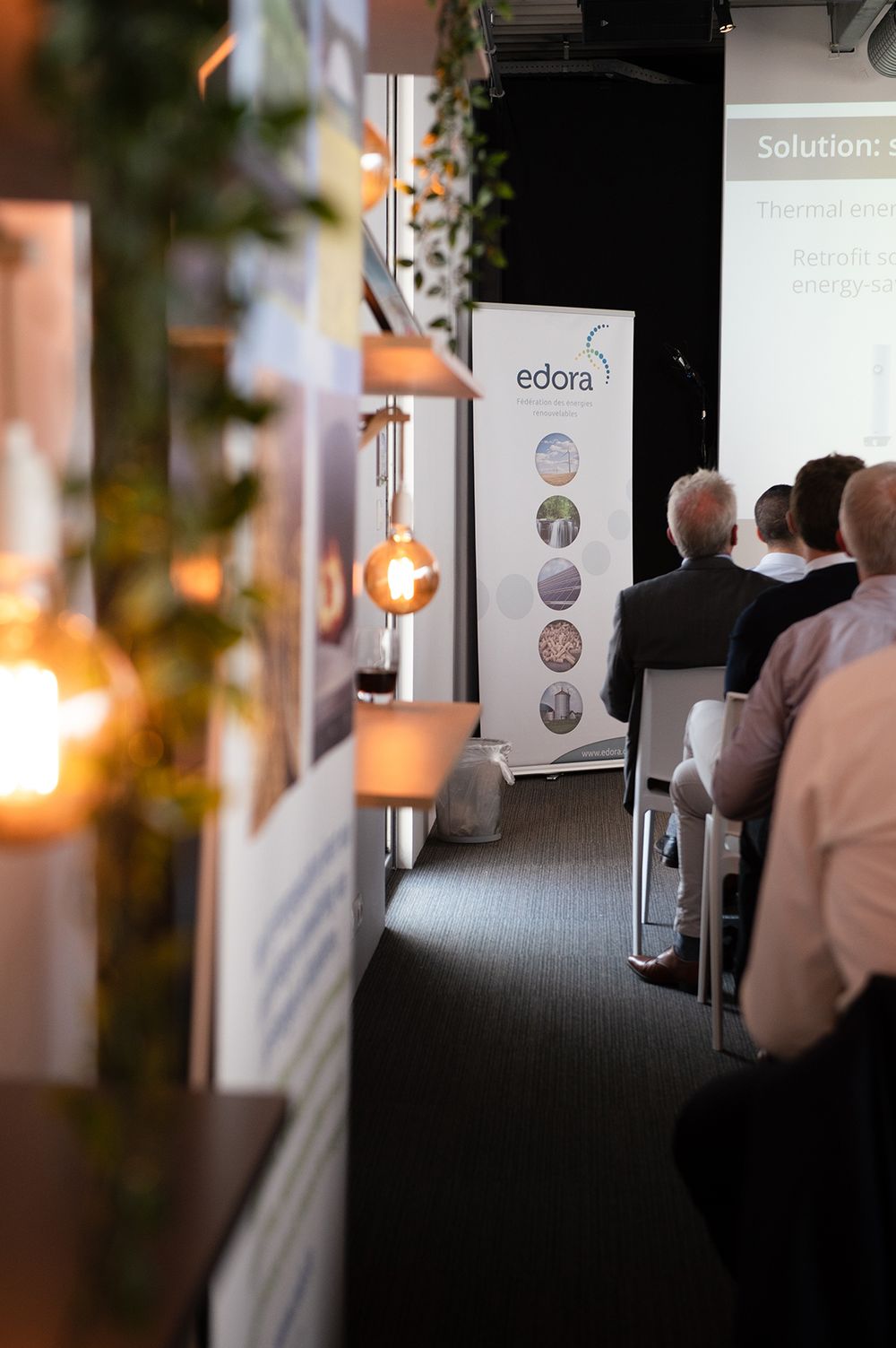Corporate presentation with attendees viewing display boards in dimly lit space.